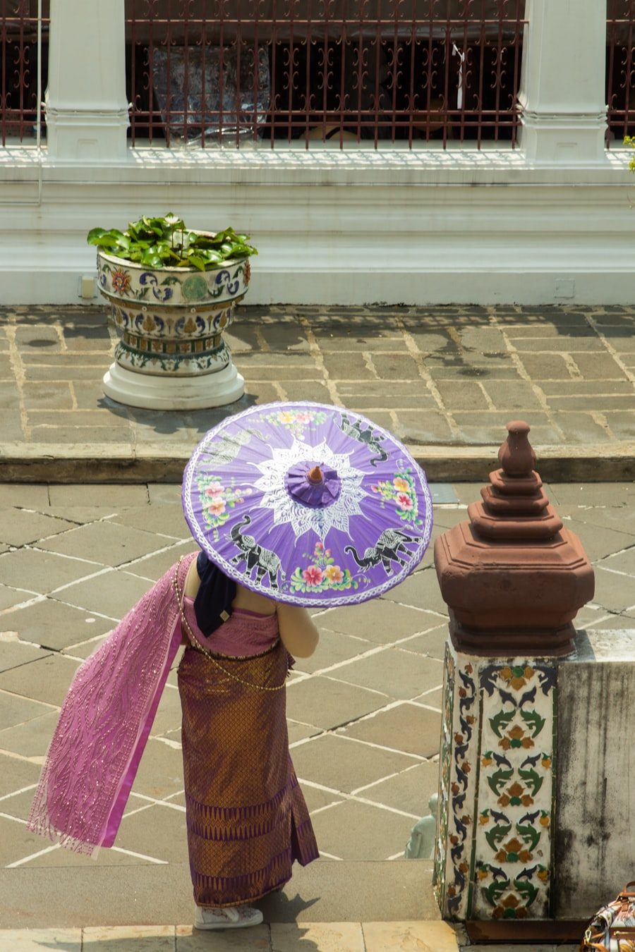 Woman in traditional Thai dress with parasol at a Bangkok temple